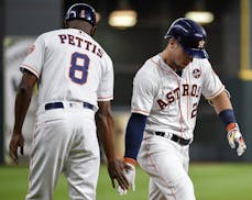 Houston Astros' Alex Bregman, right, celebrates his solo home run off Minnesota Twins starting pitcher Kyle Gibson with third base coach Gary Pettis d