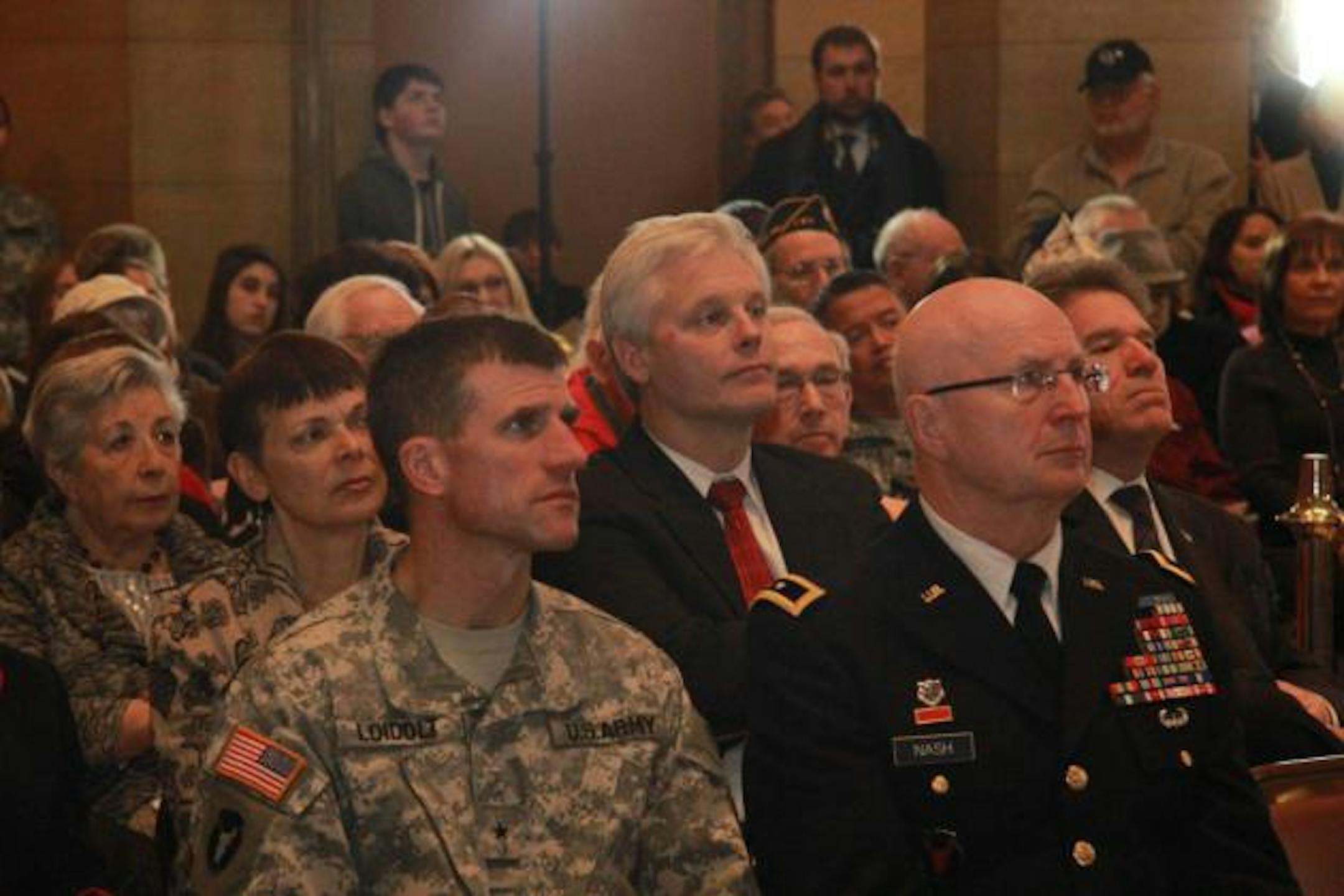 Foreground: Brigadier General Loidolt (left) with Major General Nash at the Minnesota State Capitol. Background: (L to R) Senator Sandy Pappas, Speaker Paul Thissen, and Secretary of State Mark Ritchie at the Minnesota State Capitol.