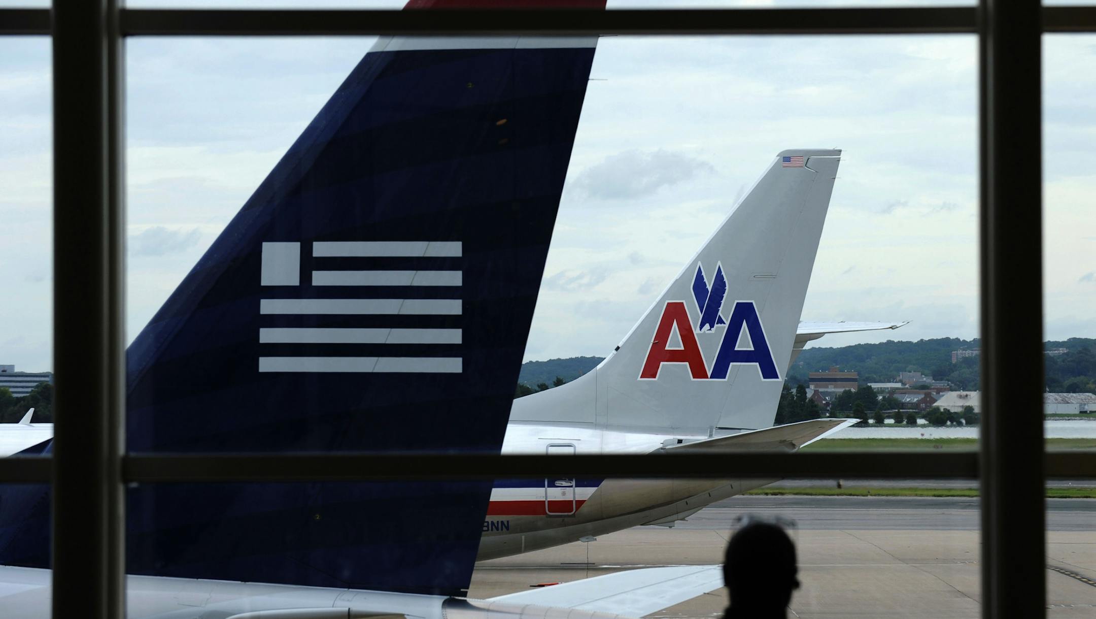 FILE- In this Tuesday, Aug. 13, 2013, file photo, an American Airlines plane and a US Airways plane are parked at Washington's Ronald Reagan National Airport in Washington.American Airlines and US Airways say that the government's opposition to their planned merger shows that it doesn't understand the airline industry. (AP Photo/Susan Walsh, File)