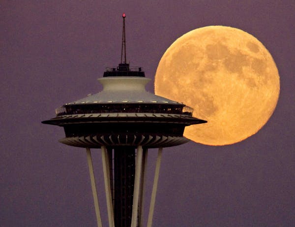 A full moon rises besides the Space Needle, Monday July 22, 2013, in Seattle. This view is from the Ursula Judkins Viewpoint, part of Smith Cove Park,