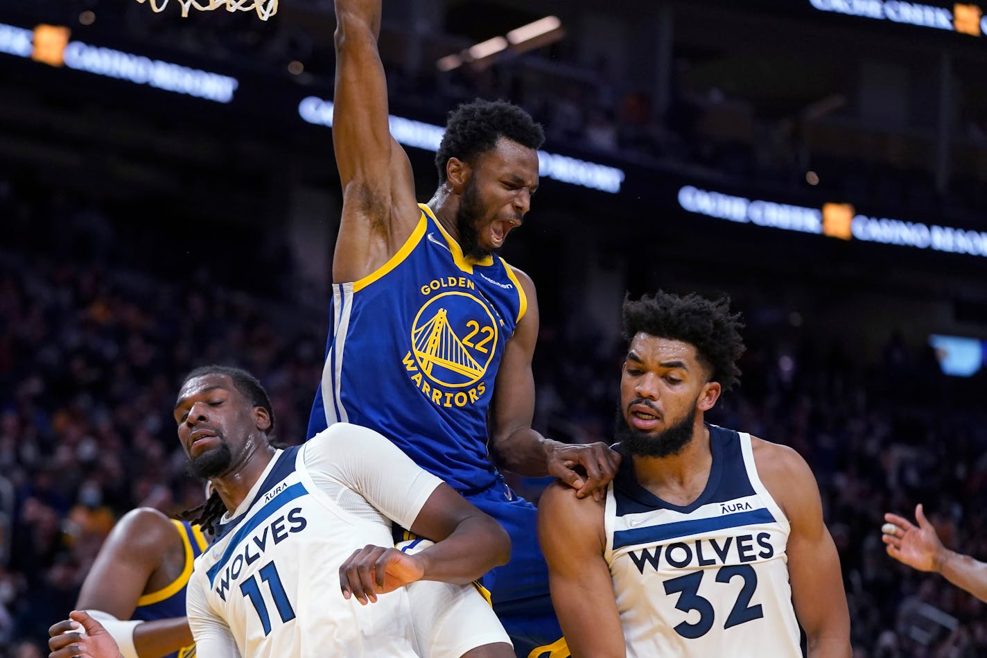 Golden State Warriors forward Andrew Wiggins (22) reacts after dunking against Minnesota Timberwolves' Naz Reid (11) and Karl-Anthony Towns (32) during the second half of an NBA basketball game in San Francisco, Wednesday, Nov. 10, 2021. (AP Photo/Jeff Chiu)