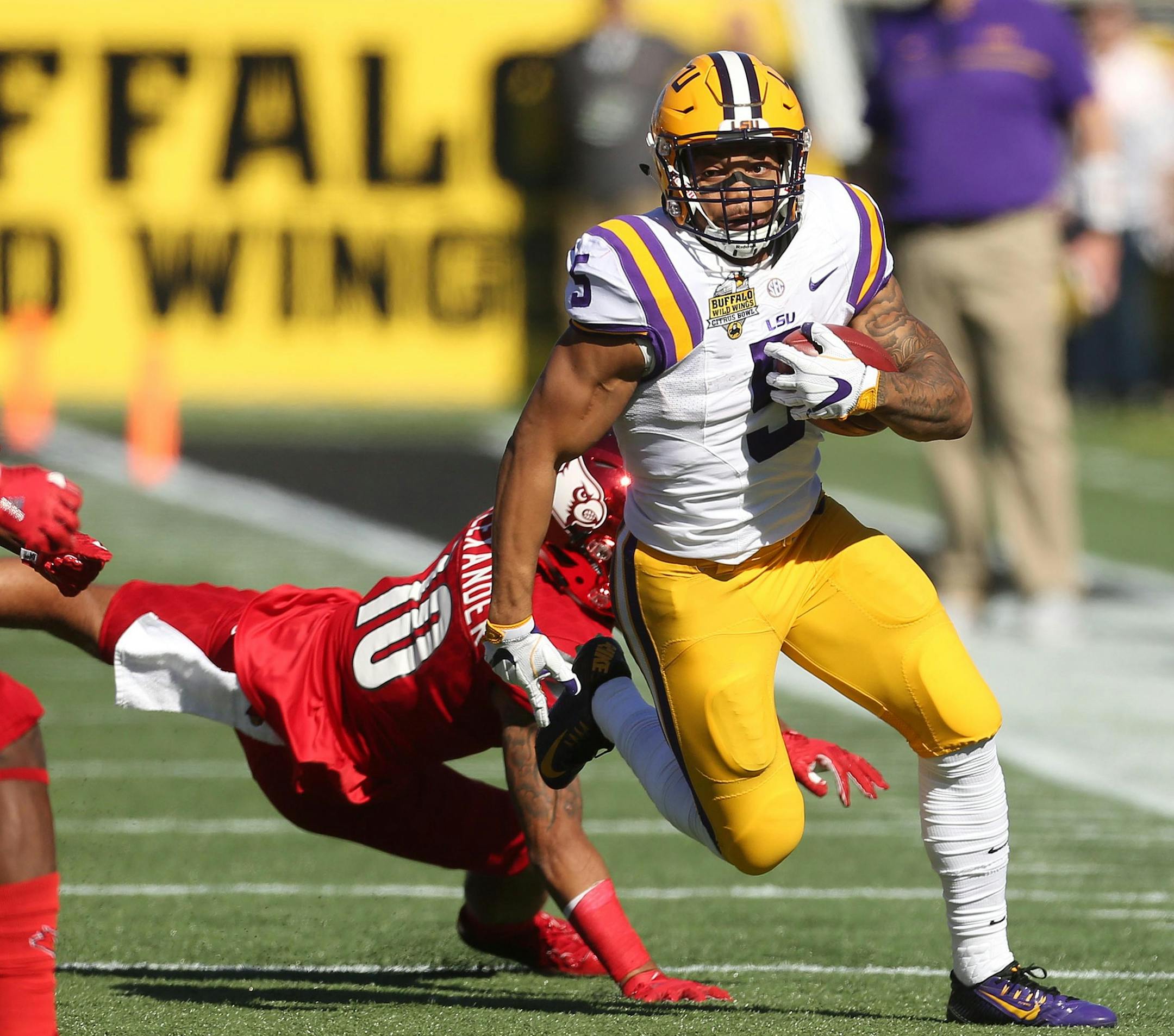 LSU running back Derrius Guice (5) runs away from Louisville cornerback Jaire Alexander (10) during the Buffalo Wild Wings Citrus Bowl at Camping World Stadium in Orlando, Fla., on Saturday, Dec. 31, 2016. LSU won, 29-9. (Stephen M. Dowell/Orlando Sentinel/TNS)