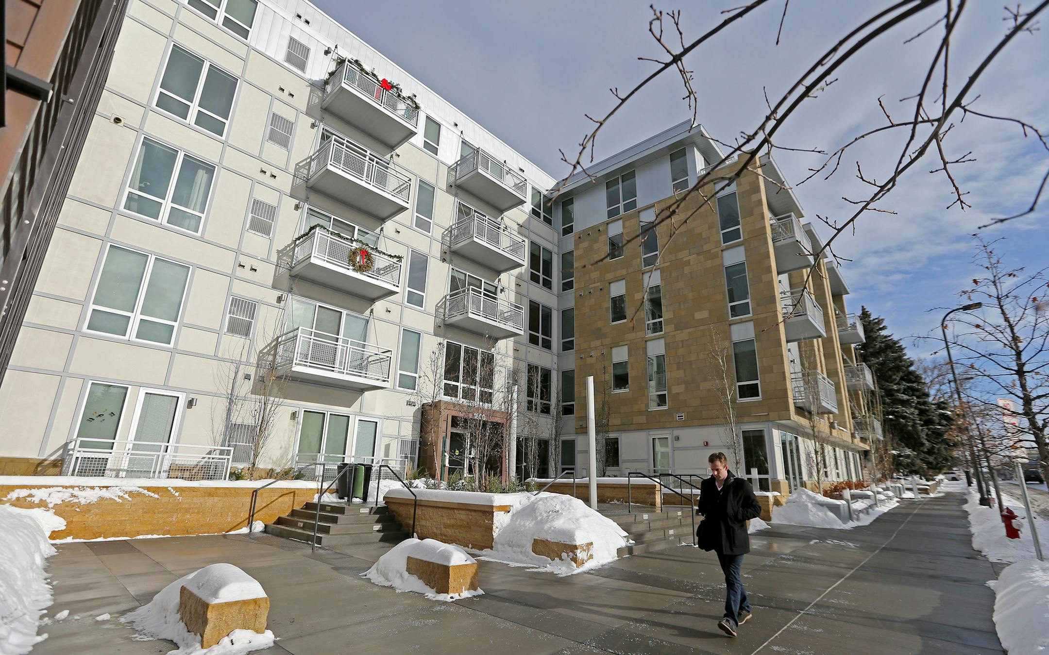 A walker made his way down a sidewalk in front of an apartment building that is the site of controversy, Friday, December 27, 2013 in Minneapolis, MN. The city of Minneapolis is suing the owner of an Uptown luxury apartment building over what the city says is the illegal discharge of groundwater into the lagoon between Isles and Calhoun.The water is being pumped out to keep the building's two stories of underground garage dry. Critics say the 55-degree groundwater is making the ice thin and dang