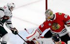 Chicago Blackhawks goalie Collin Delia, right, blocks a shot by Minnesota Wild left wing Zach Parise (11) during the third period of an NHL hockey gam