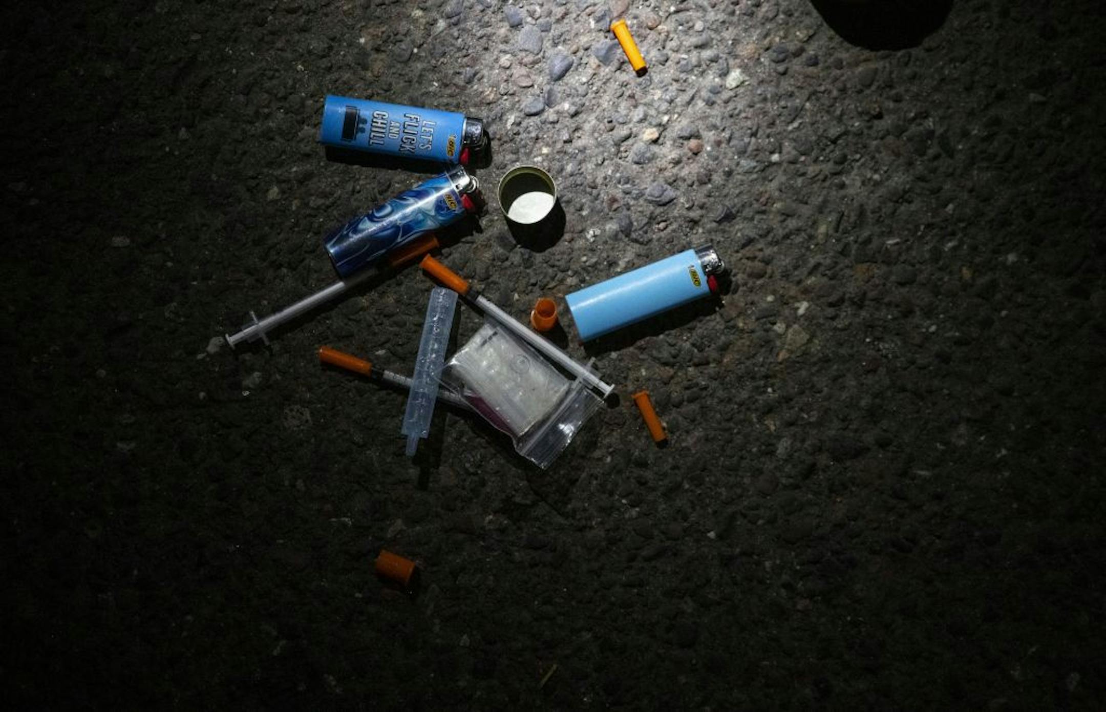 A collection of needles and lighters sat on the street next to a vehicle suspected of having drugs inside. A few grams of heroine were found in the passenger seat.