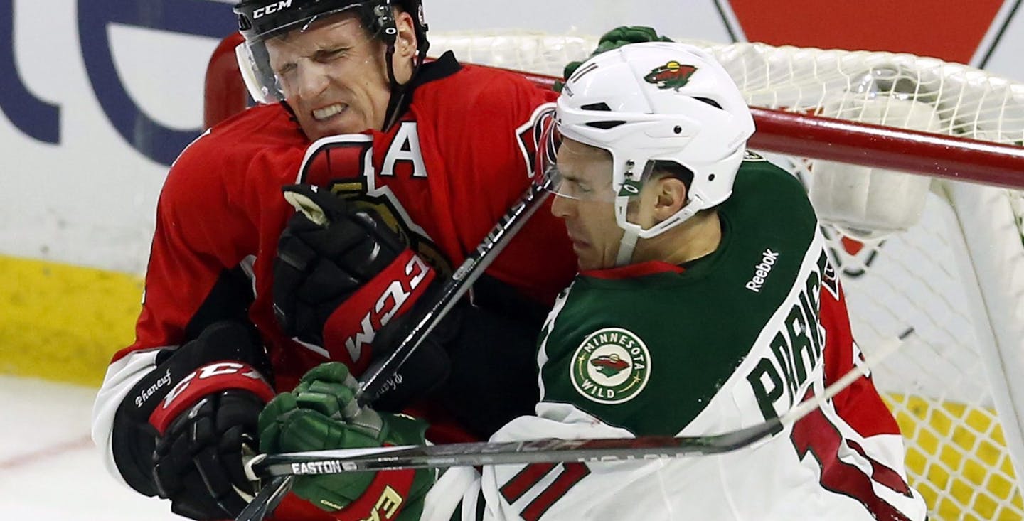 Minnesota Wild's Zach Parise (11) and Ottawa Senators' Dion Phaneuf (2) battle in front of the Senators' net during the first period of an NHL hockey game Tuesday, March 15, 2016, in Ottawa, Ontario. (Fred Chartrand/The Canadian Press via AP)