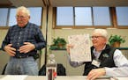 Bob Nelson (left) glued the backs of coloring sheets so Robert Fisher (right) could adhere them onto paper bags.