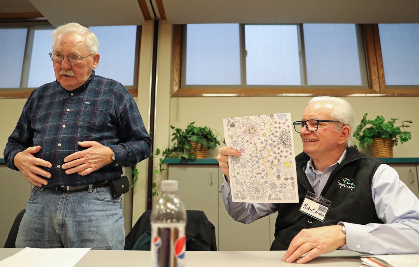 Bob Nelson (left) glued the backs of coloring sheets so Robert Fisher (right) could adhere them onto paper bags.