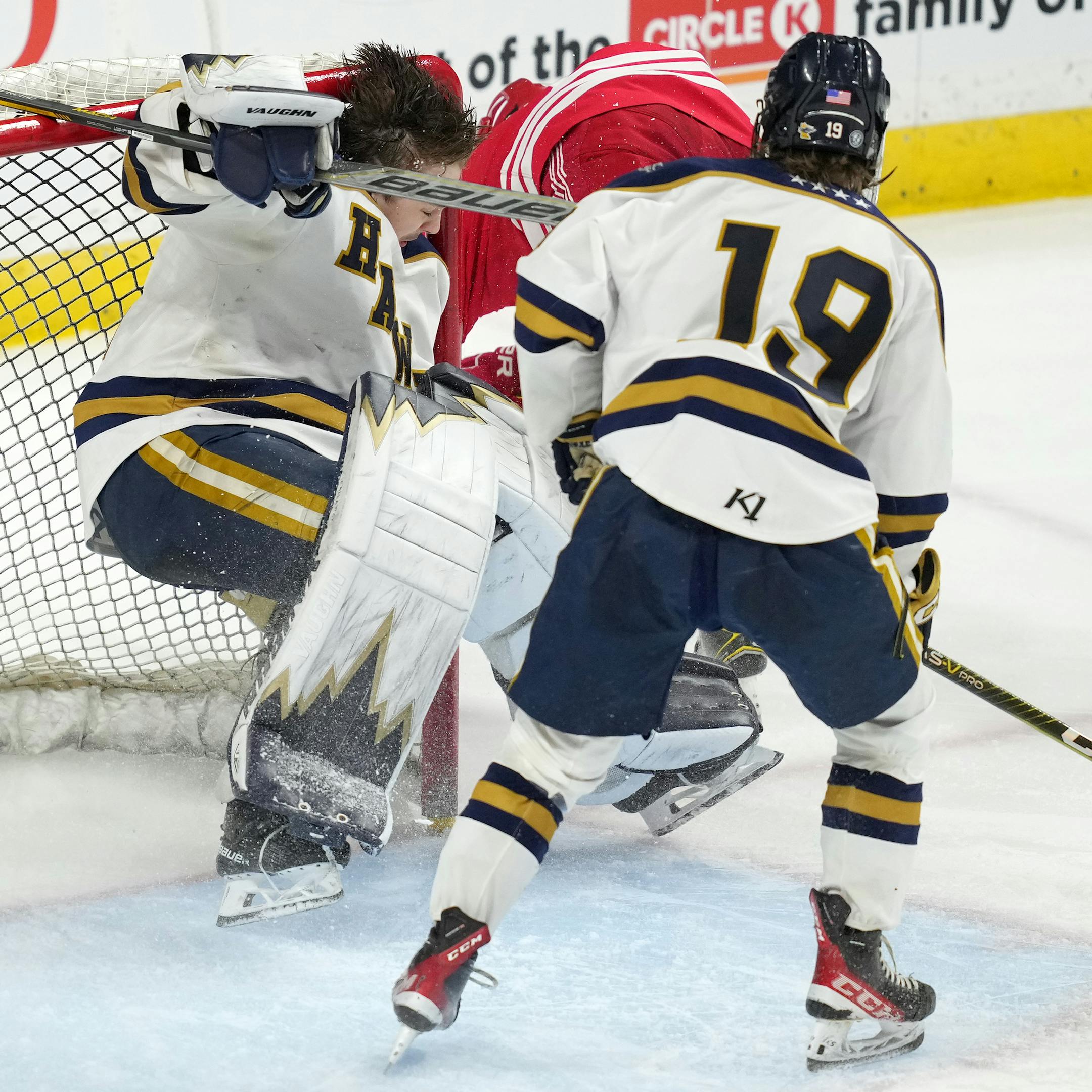 Luverne forward Elliot Domagala (12) collides with Hermantown goaltender Dane Callaway (32) as his helmet comes off in the second period of a MSHSL Class 1A quarterfinal hockey game between Luverne and Hermantown.