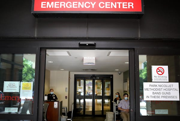 Screeners wait inside the entrance to the Park Nicollet Methodist Hospital emergency room, where they check those arriving for COVID symptoms before d