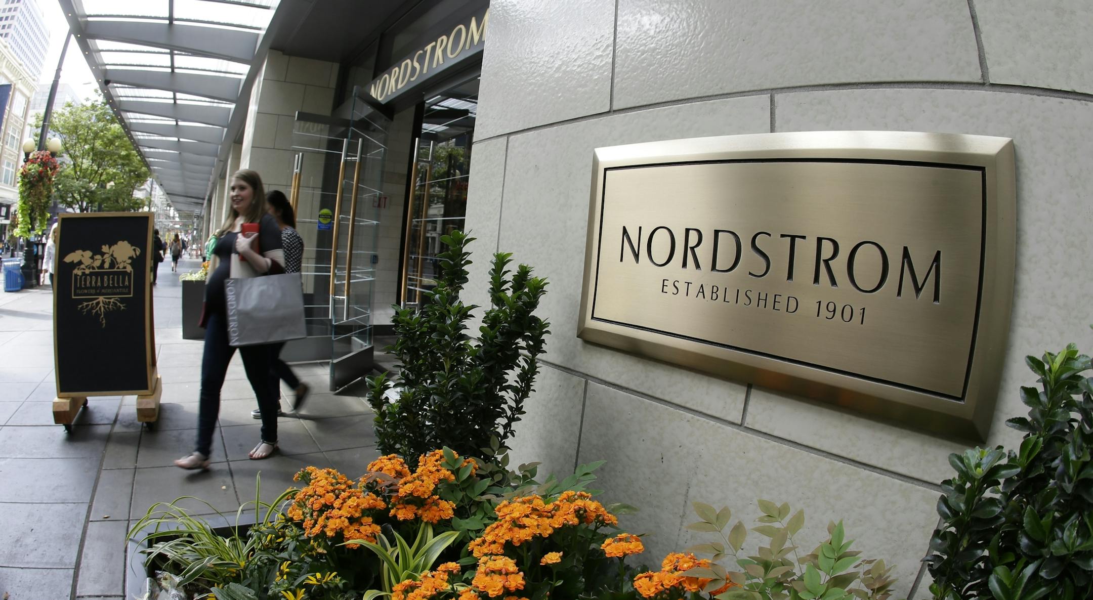 In this Wednesday, Sept. 13, 2017, photo, shoppers come and go from Nordstrom's flagship store in downtown Seattle. Nordstrom says it’s temporarily halting an exploration into taking the company private. The retailer said that a group that includes several members of the Nordstrom family plans to resume looking into a possible deal after the holiday season ends. (AP Photo/Ted S. Warren)