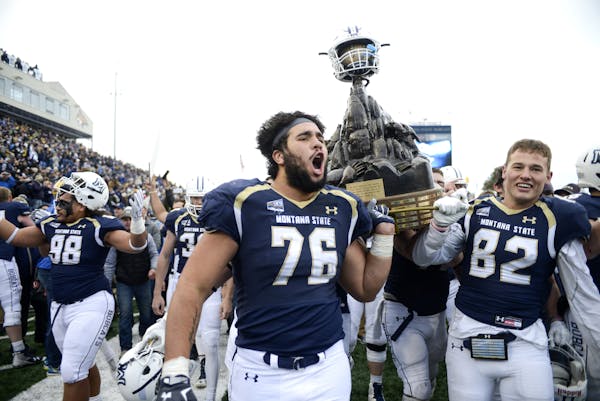 Montana State offensive lineman Lewis Kidd and wide receiver Mitchell Herbert hoist the The Great Divide Trophy into the air after a 31-20 victory ove