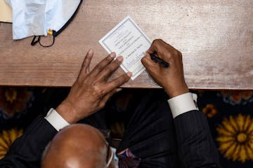 An elector signs his paper ballot for Vice President-elect Kamala D. Harris as electors cast their Electoral College votes at the Georgia State Capito