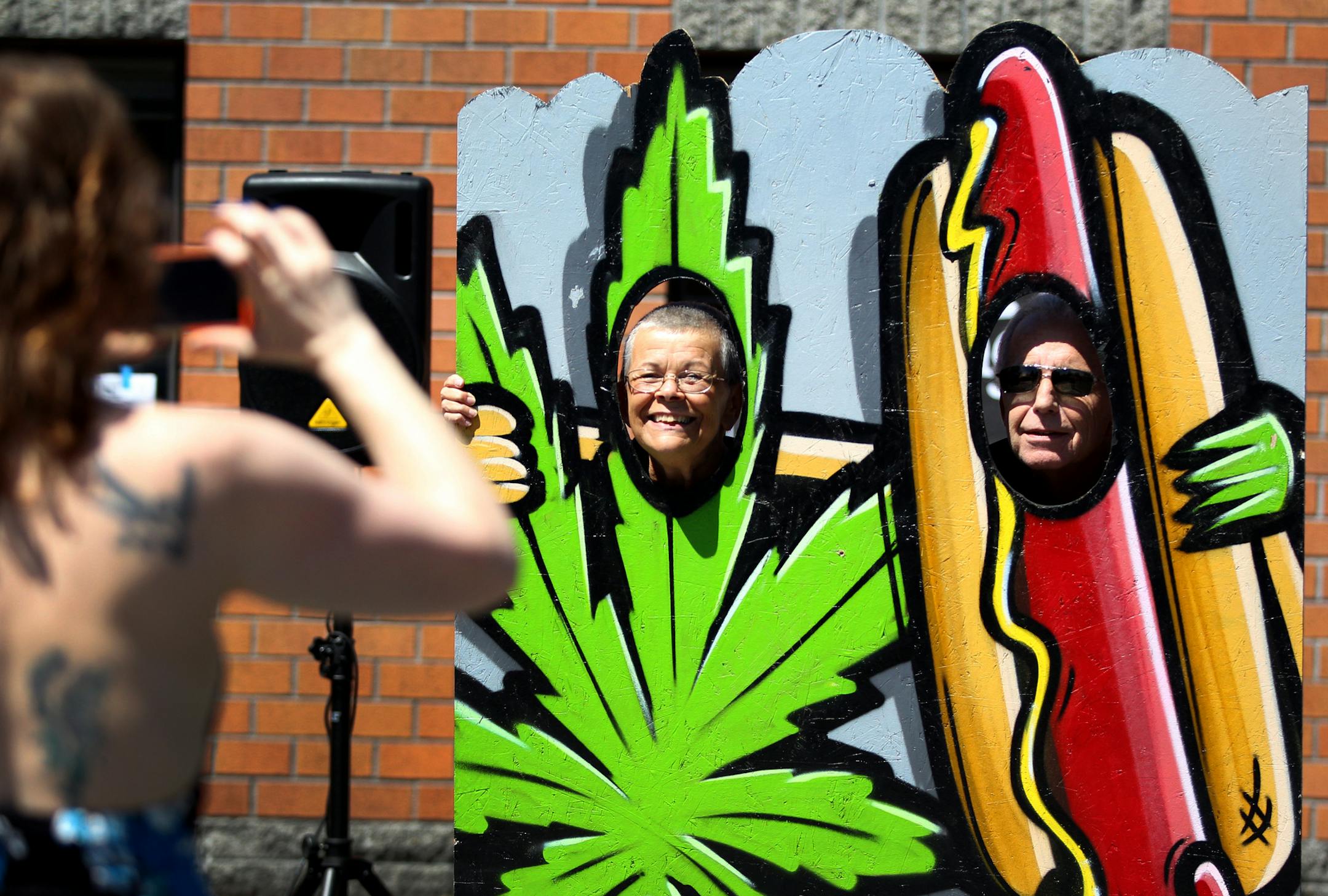 People pose for photos in cutouts near Main Street Marijuana, which began selling marijuana for recreational uses, Wednesday, July 9, 2014, in Vancouver, Wash. (AP Photo/The Oregonian, Beth Nakamura)