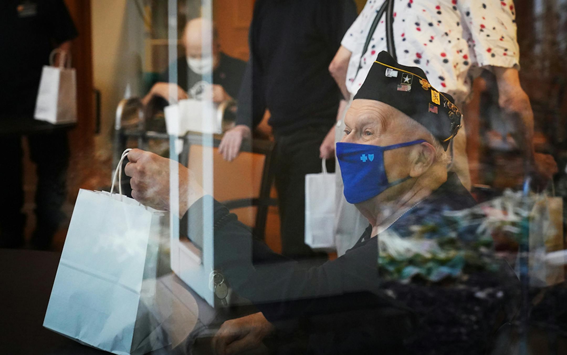 Robert Weinzierl, resident of the Waters in Plymouth, seen through a window, appeared to be happy to receive breakfast and gifts as part of the city's Veterans Day celebration.