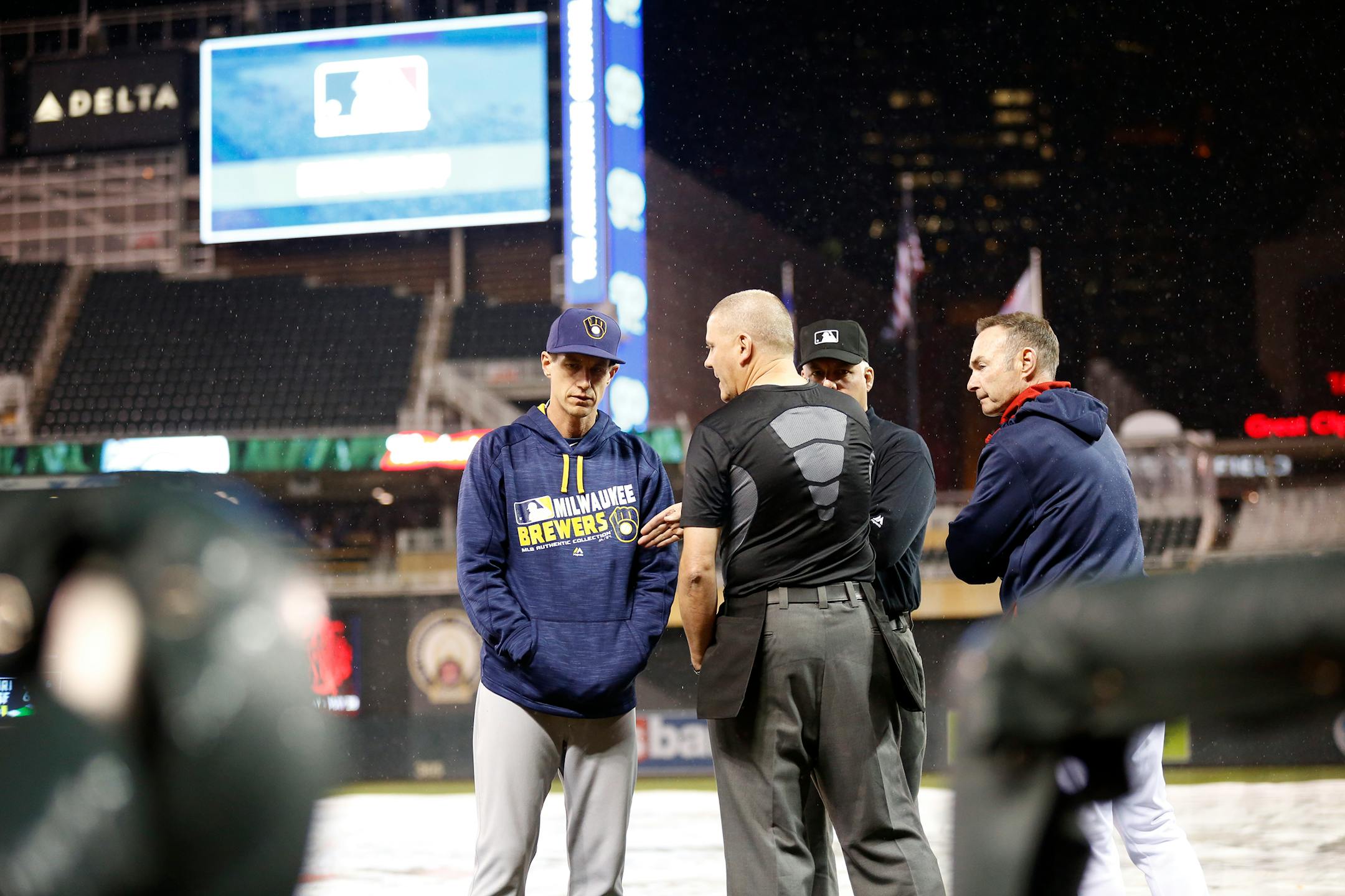 Brewers manager Craig Counsell, left, and Twins manager Paul Molitor talked with the umpiring crew during a two-hour, six-minute rain delay Monday at Target Field. The game was called after six innings, with the Twins winning 7-4.