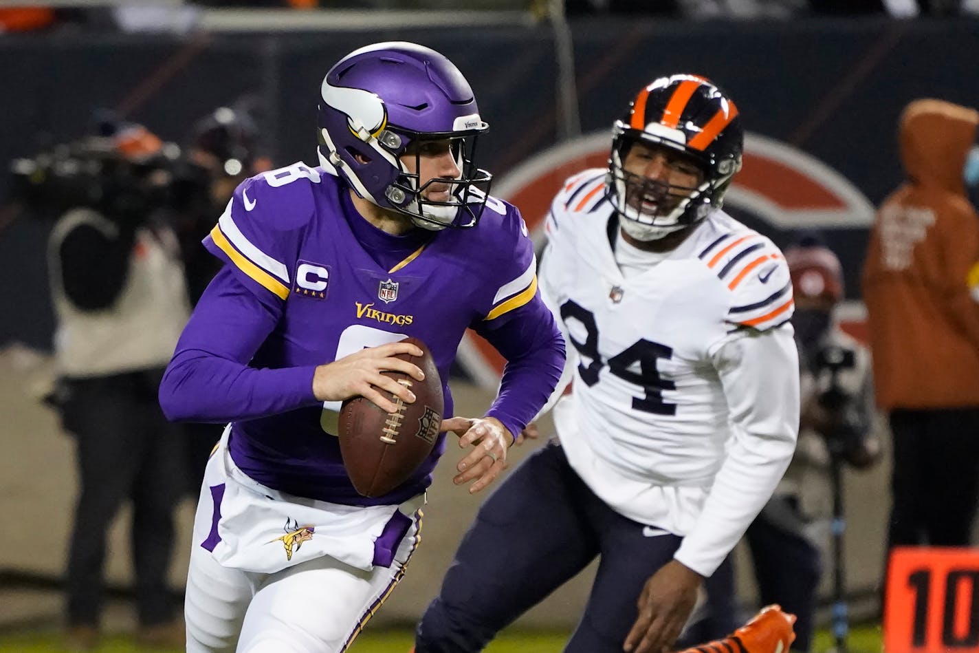 Minnesota Vikings quarterback Kirk Cousins scrambles away from pressure by Chicago Bears outside linebacker Robert Quinn during the first half of an NFL football game Monday, Dec. 20, 2021, in Chicago. (AP Photo/Charles Rex Arbogast)