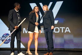 PWHL Minnesota assistant coach Mira Jalosuo, right, shakes hands with second-round draft pick Britta Curl, with St. Paul Mayor Melvin Carter at left d