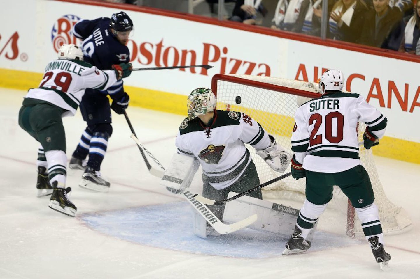 Winnipeg Jets' Bryan Little (18) scores against Minnesota Wild goaltender Darcy Kuemper (35) as he is checked by Jason Pominville (29) with Ryan Suter (20) in front of the net during first-period NHL hockey game action in Winnipeg, Manitoba, Sunday, Oct. 25, 2015.