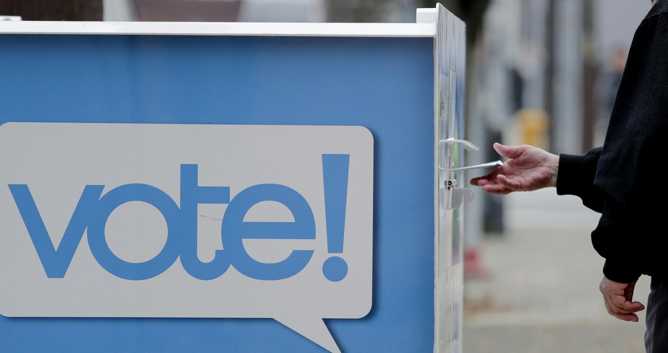 A voter drops a ballot into a ballot drop box Monday, Nov. 4, 2019, in Seattle. Voters in Washington state have a crowded ballot to fill out for this week's election, with a referendum on affirmative action and an initiative on the price of car tabs among the things they are being asked to decide. (AP Photo/Elaine Thompson)