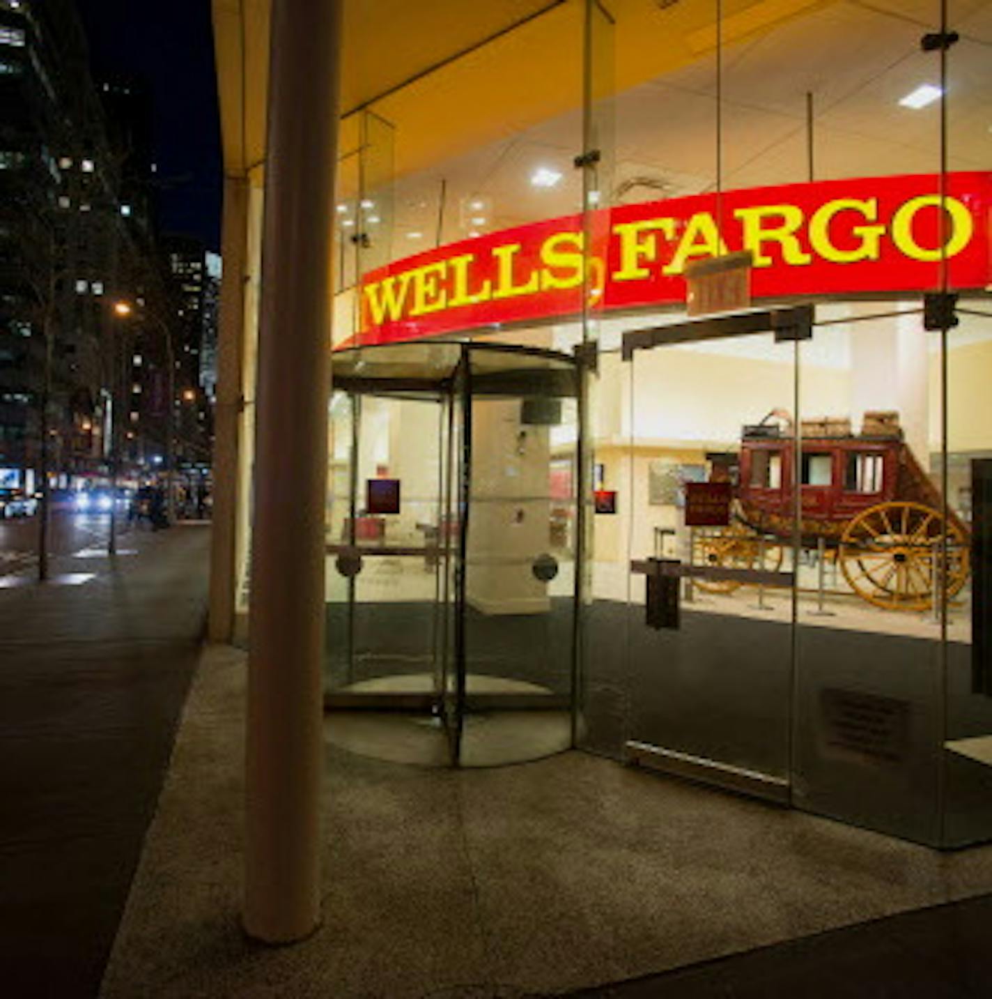 Pedestrians pass in front of a Wells Fargo & Co. bank branch at night in New York, U.S., on Monday, April 7, 2014. Wells Fargo & Co. is expected to release earnings figures on April 11. Photographer: Craig Warga/Bloomberg ORG XMIT: 484389669