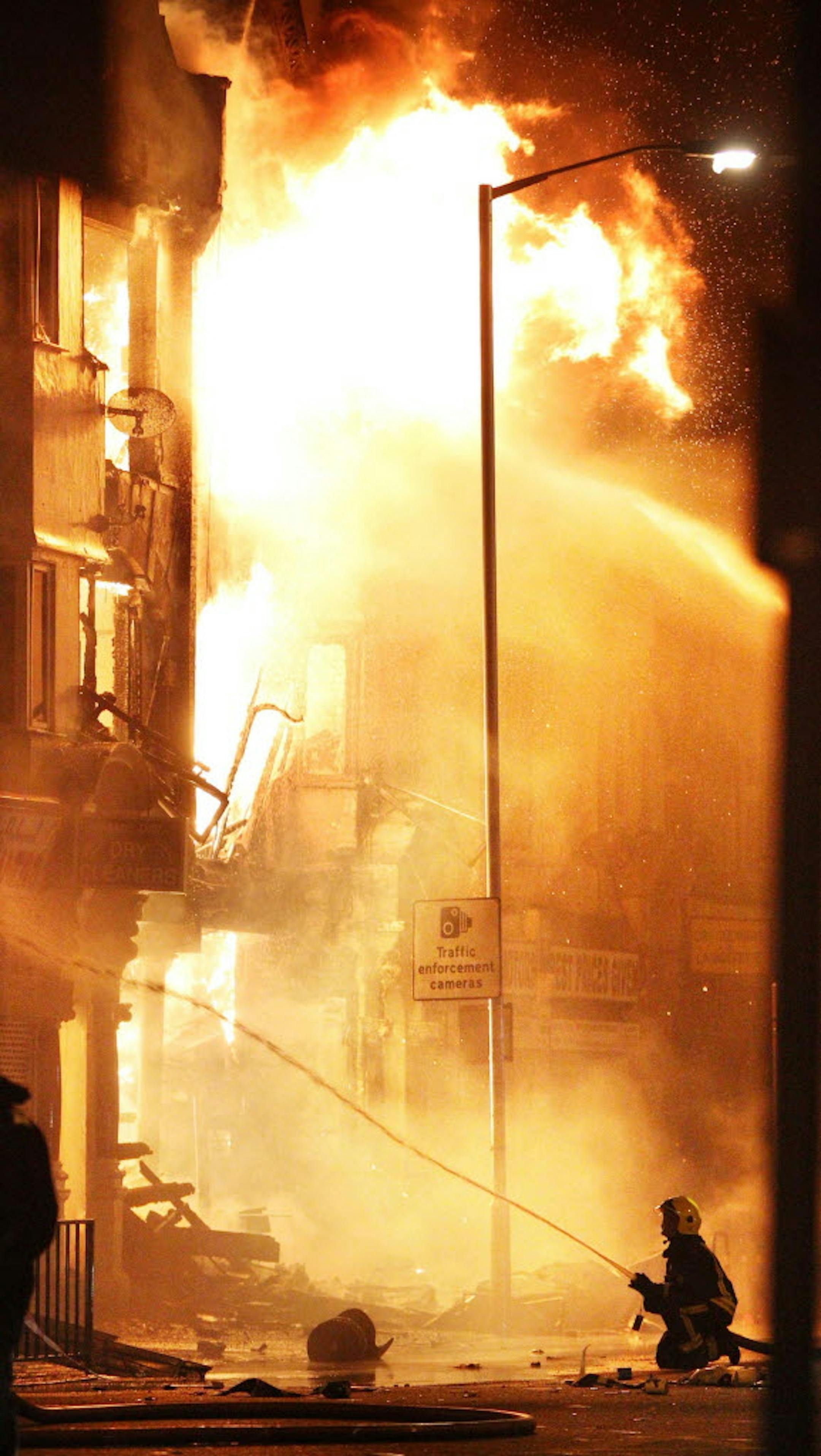 A firefighter attempts to extinguish a blaze on a building near Reeves Corner in Croydon, south London Tuesday, AP photo by Lewis Whyld