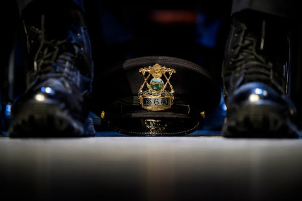 A St. Paul police academy cadet’s hat rested between their feet during a 2022 graduation ceremony.