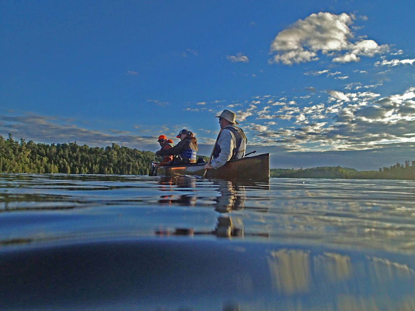 A beautiful summer evening in the Boundary Waters Canoe Area Wilderness. A canoe full of anglers appeared as if a painting.