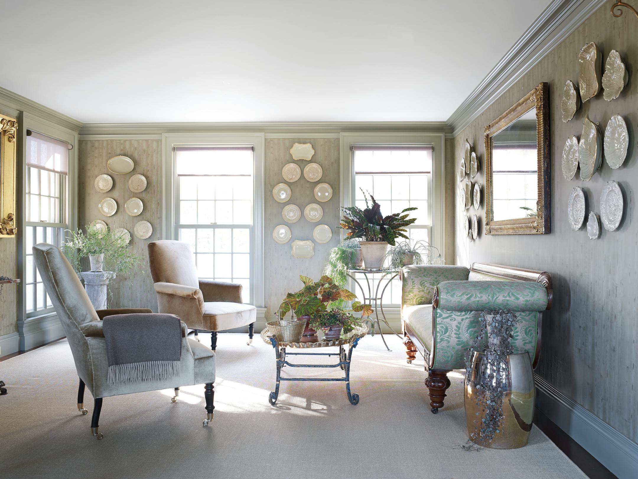 BC-ASK-MARTHA-BEDFORD-INTERIORS-ART-NYTSF — To turn a small, underutilized dining room into a comfortable spot for all Martha's new-to-her activities (breakfast at home, Zoom calls), she pulled beloved pieces from storage, like this Federal sofa originally bought for Turkey Hill, her previous home in Connecticut. It was reupholstered with Fortuny fabric she had saved, and the armchairs were re-covered in Schumacher silk velvet. "The velvet is a fabulous olive-y gold color," says Martha. "My favorite." For a place to rest a cappuccino (or cocktail), an iron stand she found while antiquing in Maine was topped with one of her brass trays. Items from the garden — a French metal table, a stool made by friend Christopher Spitzmiller — hold potted plants, including begonias and moplike green Rhipsalis. The cashmere throw is by Sferra. (Pieter Estersohn/Martha Stewart Living Online) — ONLY FOR USE WITH ARTICLE SLUGGED — BC-ASK-MARTHA-BEDFORD-INTERIORS-ART-NYTSF — OTHER USE PROHIBITED.