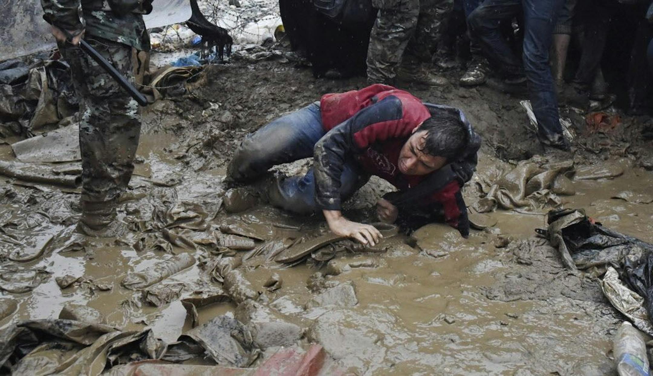 A man falls down as he tries to pass from the borders from the northern Greek village of Idomeni to southern Macedonia, Thursday, Sept. 10, 2015. Thousands of people, including many families with young children, braved torrential downpours to cross Greece�s northern border with Macedonia early Thursday, after Greek authorities managed to register about 17,000 people on the island of Lesbos in the space of a few days, allowing them to continue their journey north into Europe.