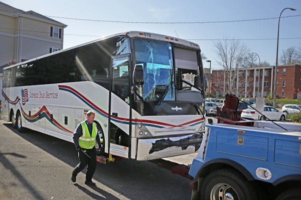 Tom Lynch of Twins Cities Towing and Recovery prepares one of two buses involved in an earlier accident for towing. Two Washington Redskins team buses