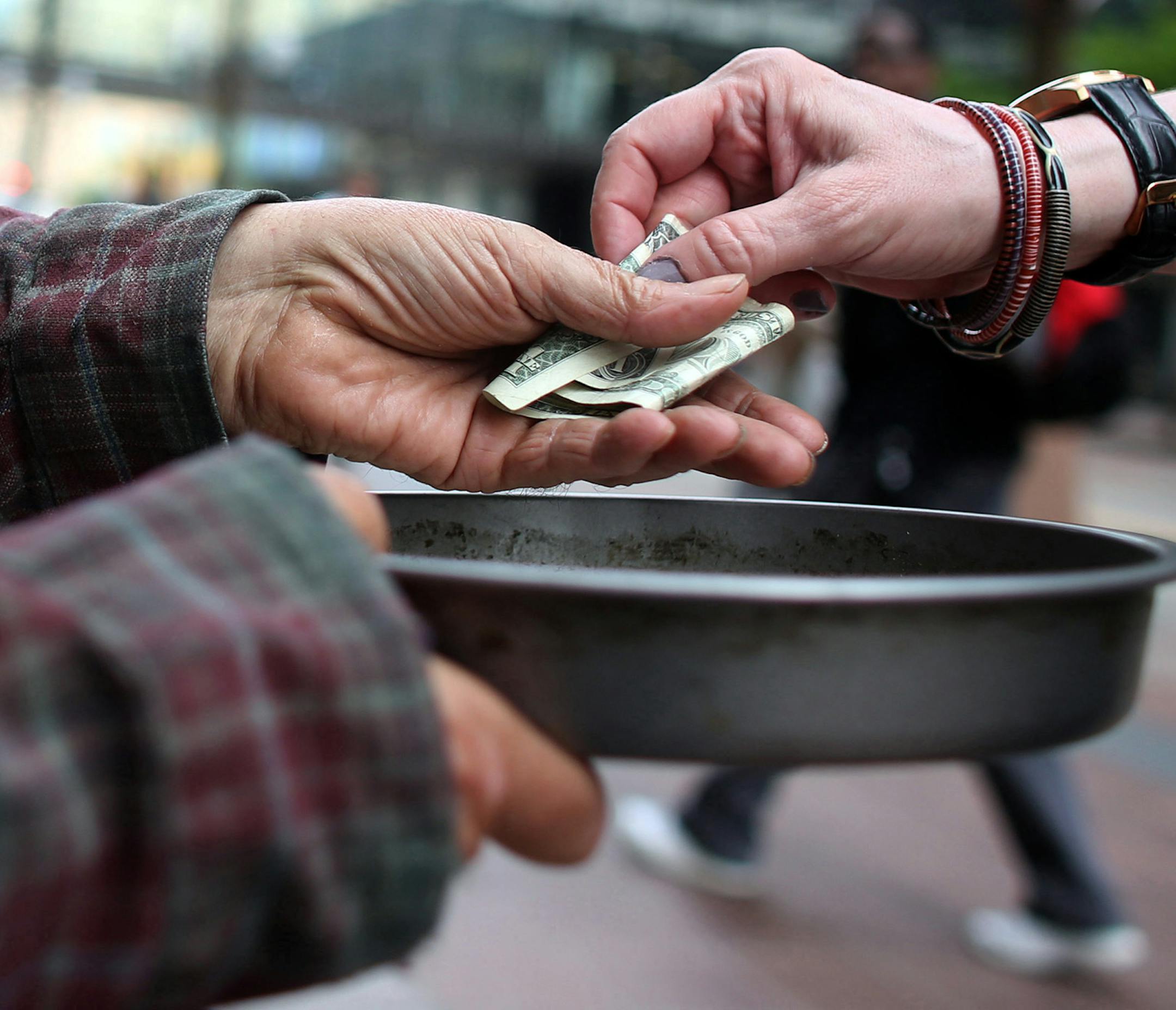Edwin Schall got a dollar from a passerby as he held out a pan t get money for food along Nicollet Ave. ] (KYNDELL HARKNESS/STAR TRIBUNE) kyndell.harkness@startribune.com In downtown Minneapolis, Min. Tuesday, June 3, 2014. A new campaign in Minneapolis wants to end panhandling. The "Give Real Change Campaign" which has billboards in Downtown Minneapolis, is telling residents to end panhandling and give to a charitable organization instead. ORG XMIT: MIN1406031618130714 ORG XMIT: MIN140610104739