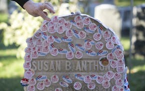 A woman places a voting sticker on the headstone of Susan B. Anthony, a women's suffrage pioneer, on Election Day in Rochester, N.Y., Nov. 8, 2016.