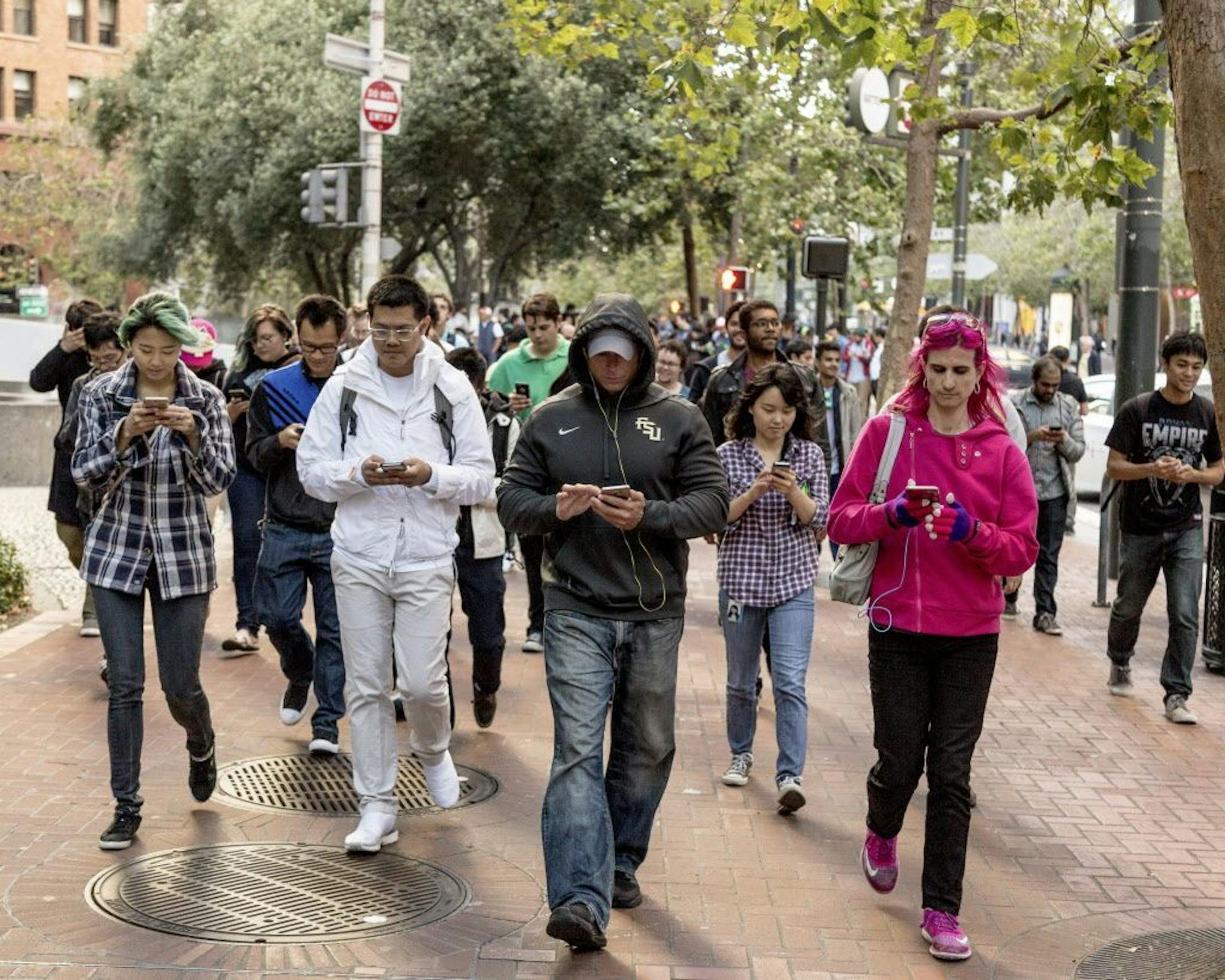 People walk up Market Street playing Pokemon Go, an augmented reality game, during a Pokemon Go Pub Crawl in San Francisco, July 20, 2016. Pokemon Go has fast become a nationwide phenomenon, with millions downloading the game and playing it just about everywhere.
