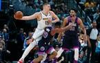 Denver Nuggets center Nikola Jokic, back left, looks to pass the ball as Timberwolves guard Josh Okogie, left front, and center Karl-Anthony Towns def