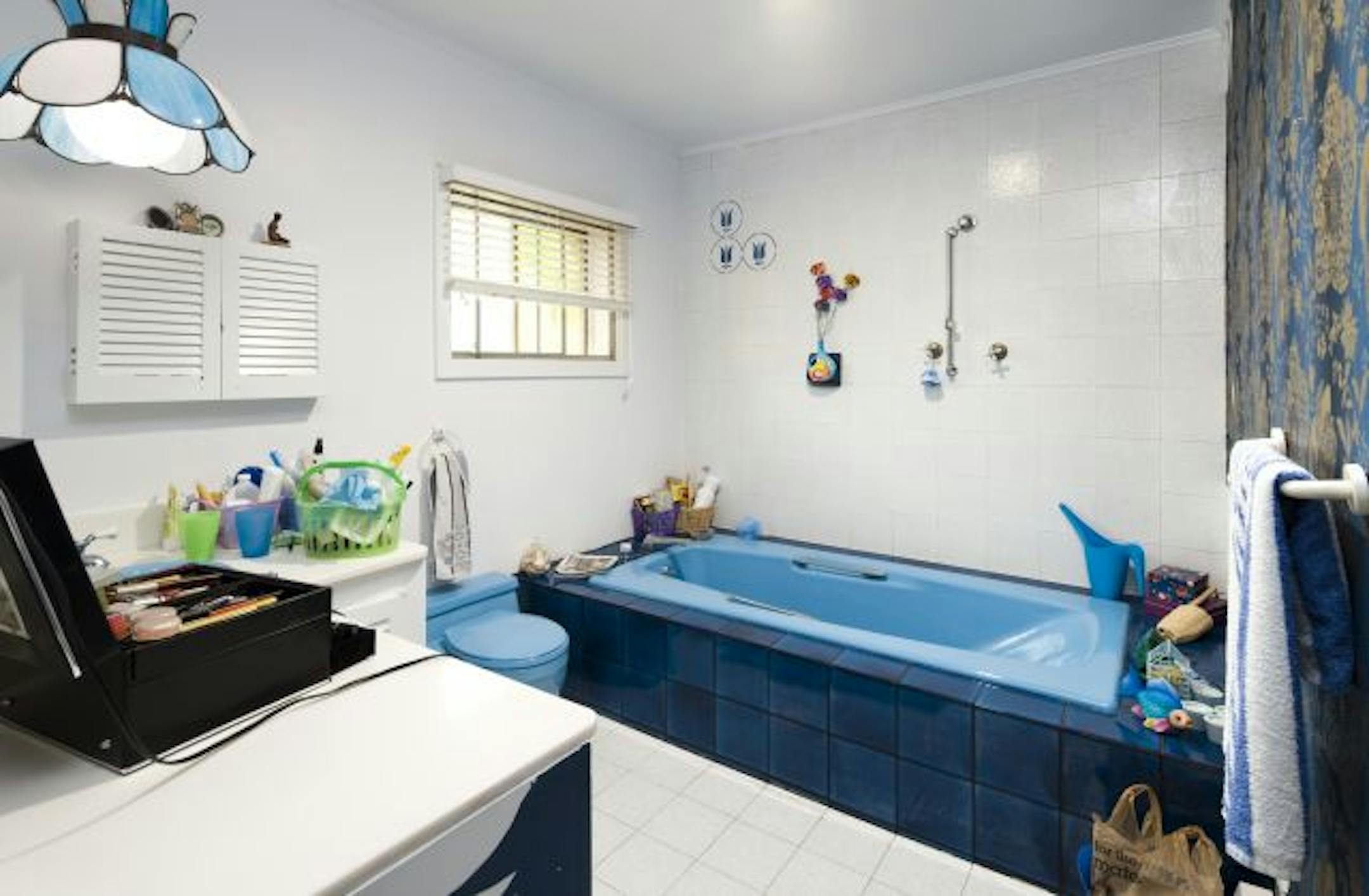 Before: Cracked floor tiles, a chipped countertop, nonfunctional baseboard heater and a little toilet that was tricky to flush left this dated blue bathroom prime for a makeover.