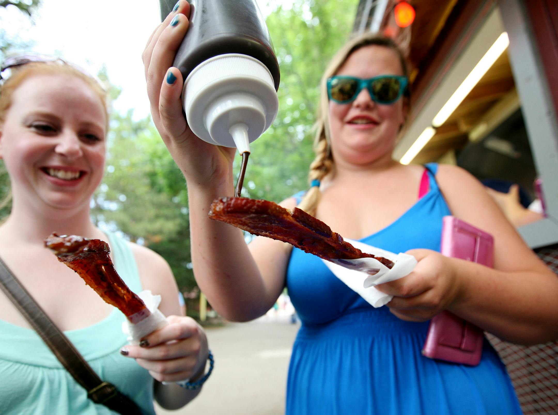 Sisters Britney Payne, left, of Inver Grove Heights and Alexis Geving of Ogilvie drizzle chocolate on their bacon from Big Fat Bacon at the Minnesota State Fair August 25, 2013.