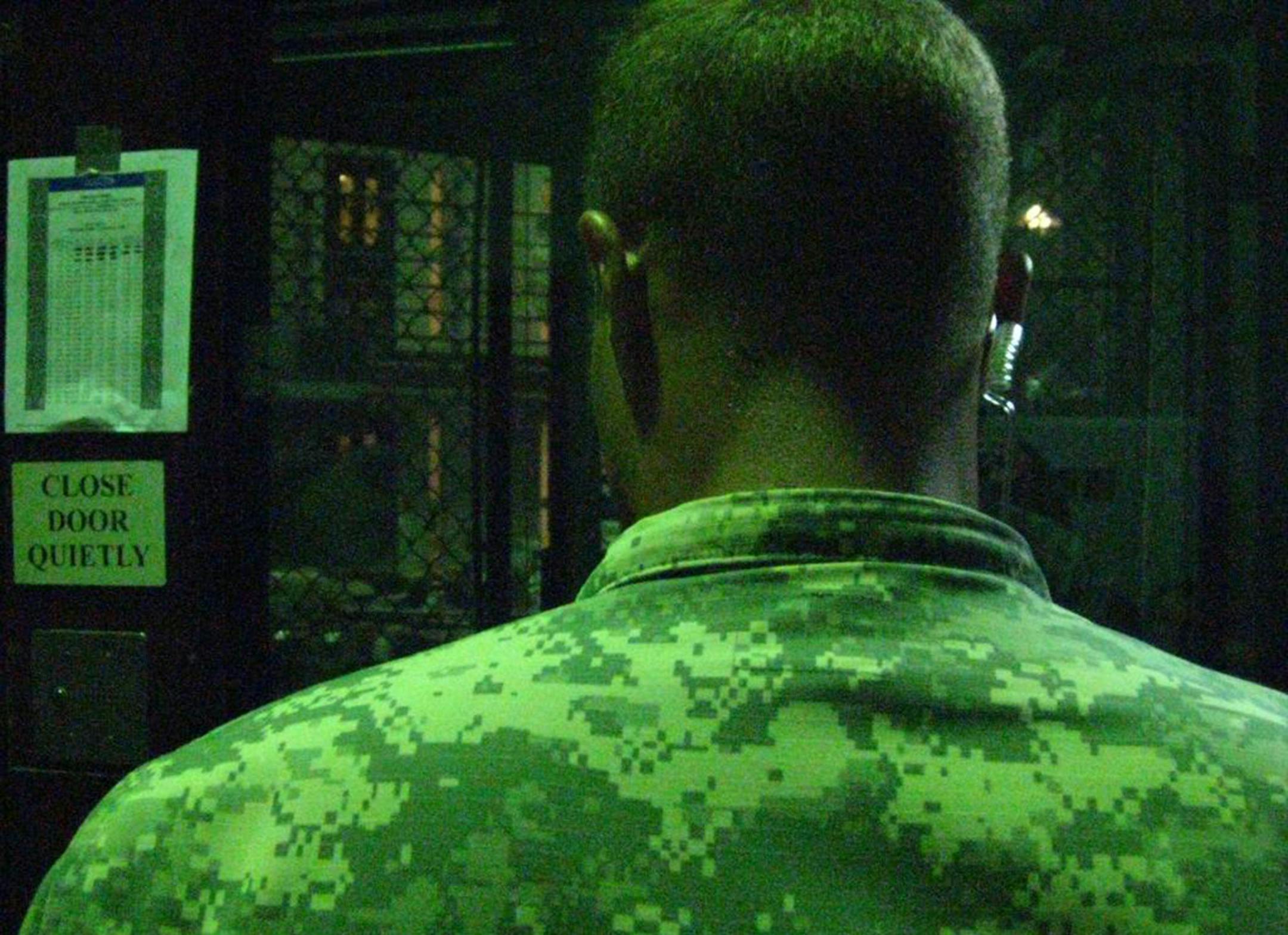An Army guard stands watch outside a cellblock at the communal Camp 6 prison at the Guantanamo Detention Center on Saturday, June 3, 2017, in an image approved for release by the U.S. military. To his left, pasted on the wall: A Ramadan prayer schedule. (Carol Rosenberg/Miami Herald/TNS)