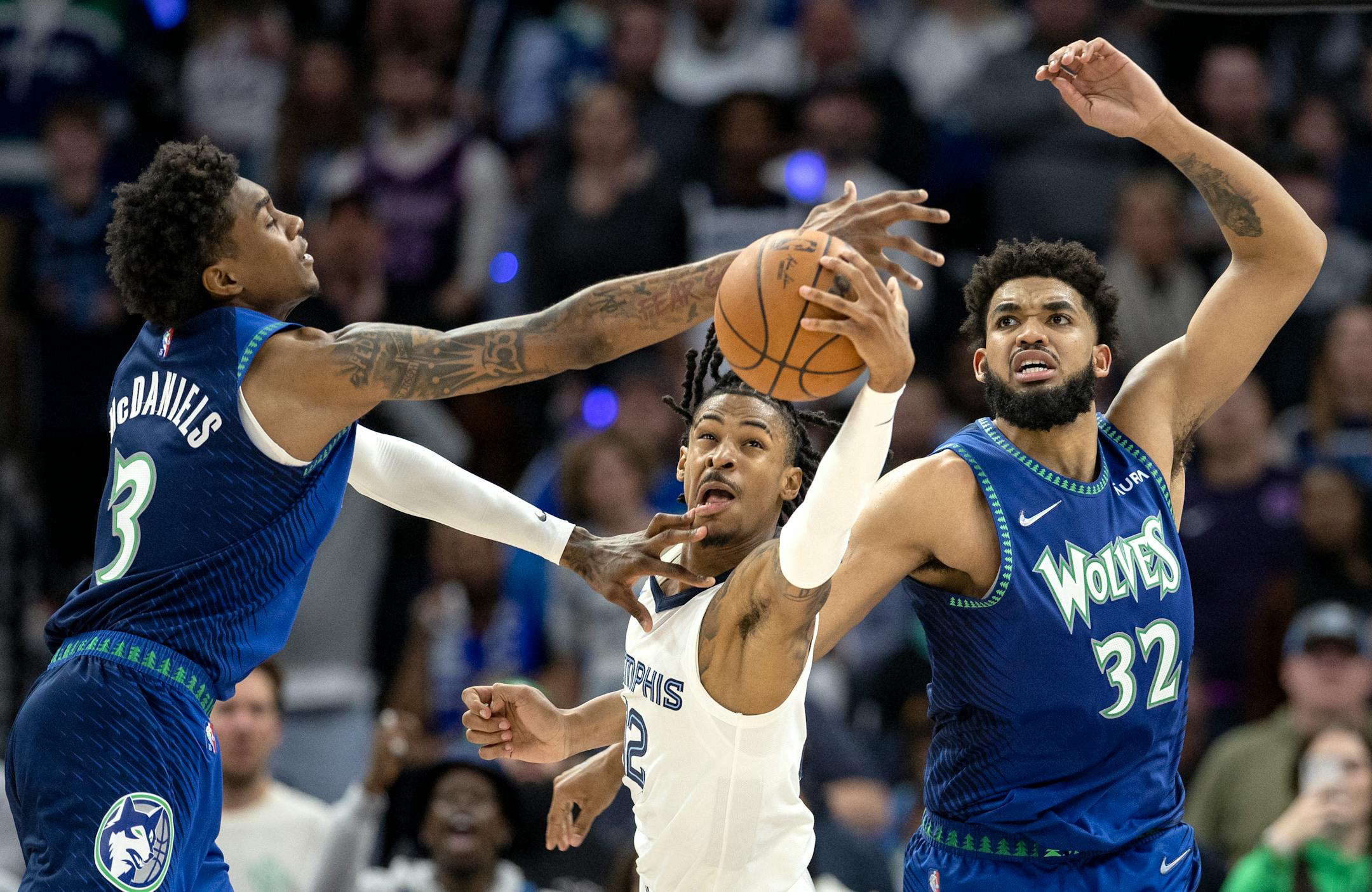 Jaden McDaniels (3) and Karl Anthony-Towns (32) of the Minnesota Timberwolves fight for the ball with Ja Morant (12) of the Memphis Grizzlies in the fourth quarter.