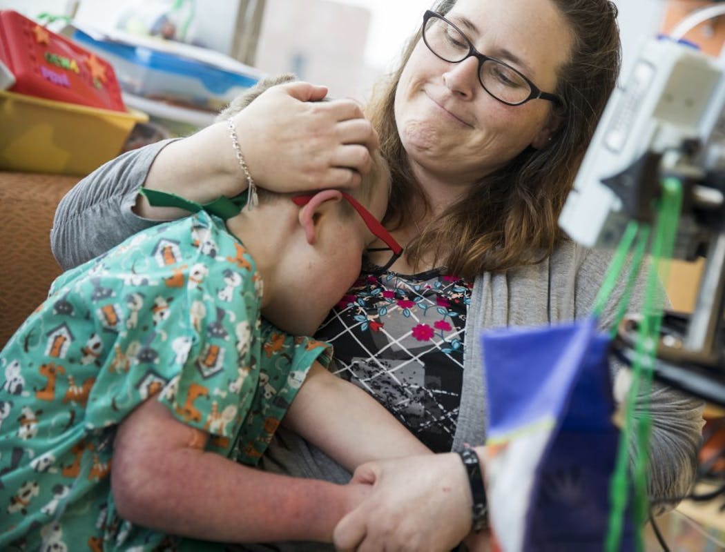 Eddie Kunze, 10, calms down a bit in the arms of his mother Christina in their hospital room.