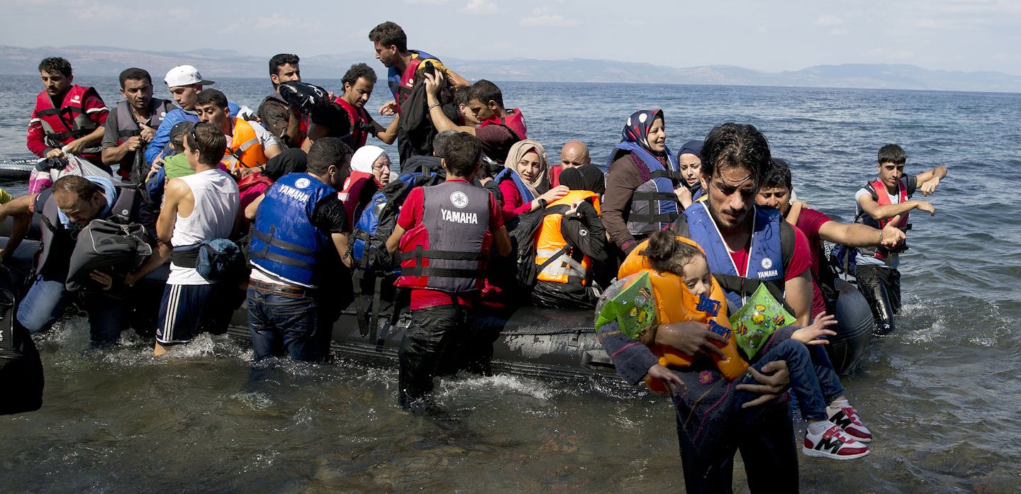 A man carries a child as migrants and refugees arrive on a dinghy after crossing from Turkey to Lesbos island, Greece, Tuesday, Sept. 8, 2015. The island of some 100,000 residents has been transformed by the sudden new population of some 20,000 refugees and migrants, mostly from Syria, Iraq and Afghanistan. (AP Photo/Petros Giannakouris) ORG XMIT: MIN2015090809031209