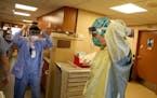 Healthcare workers don protective equipment before treating a COVID-19 patient in an ICU at Bethesda Hospital in St. Paul in May.