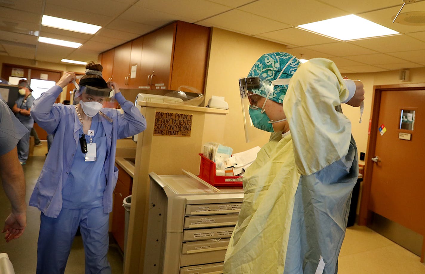 Healthcare workers don protective equipment before treating a COVID-19 patient in an ICU at Bethesda Hospital in St. Paul in May.