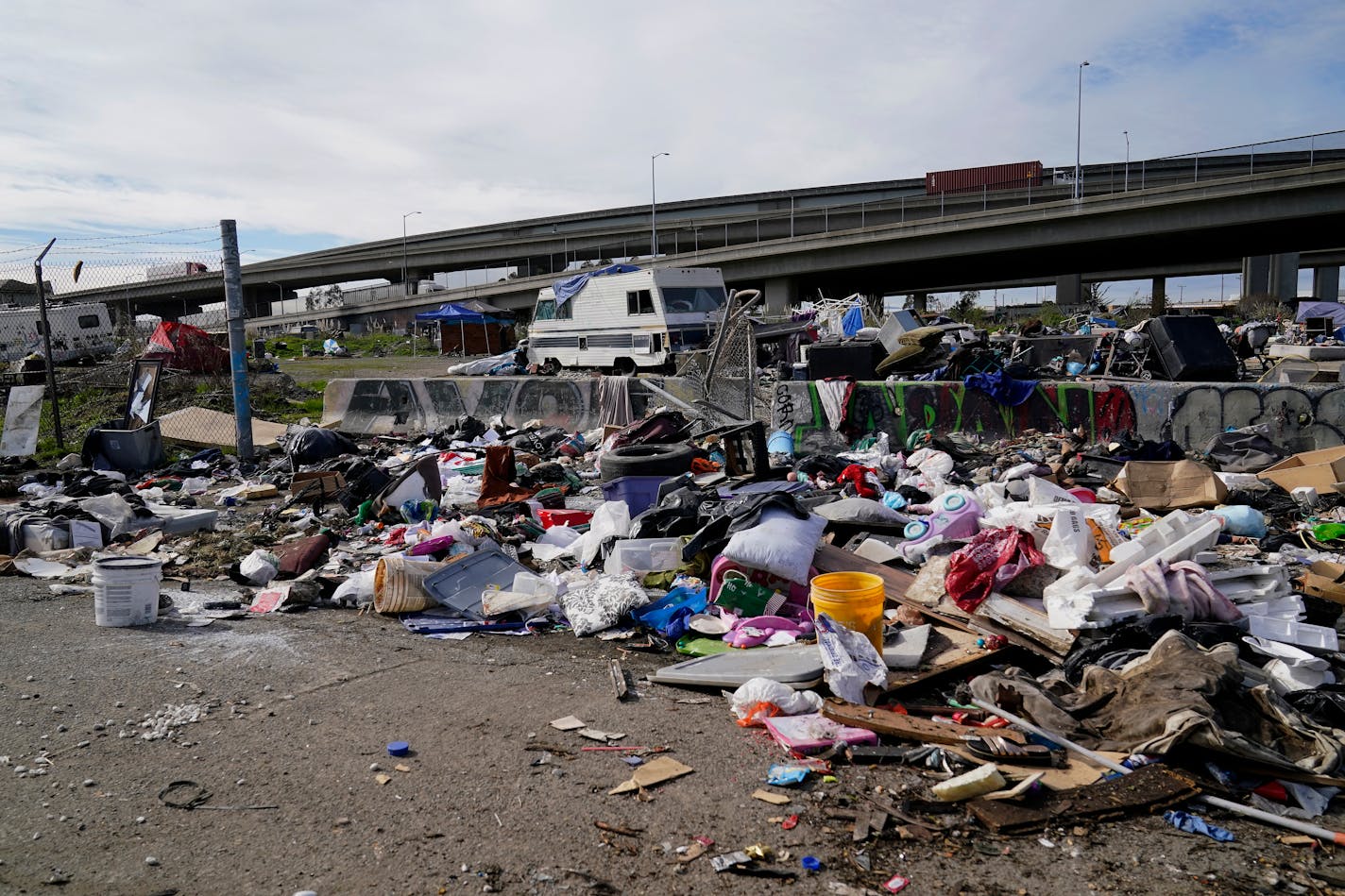 Traffic moves above an RV and debris near a homeless encampment in Oakland, Calif., Thursday, Feb. 18, 2021. (AP Photo/Jeff Chiu)