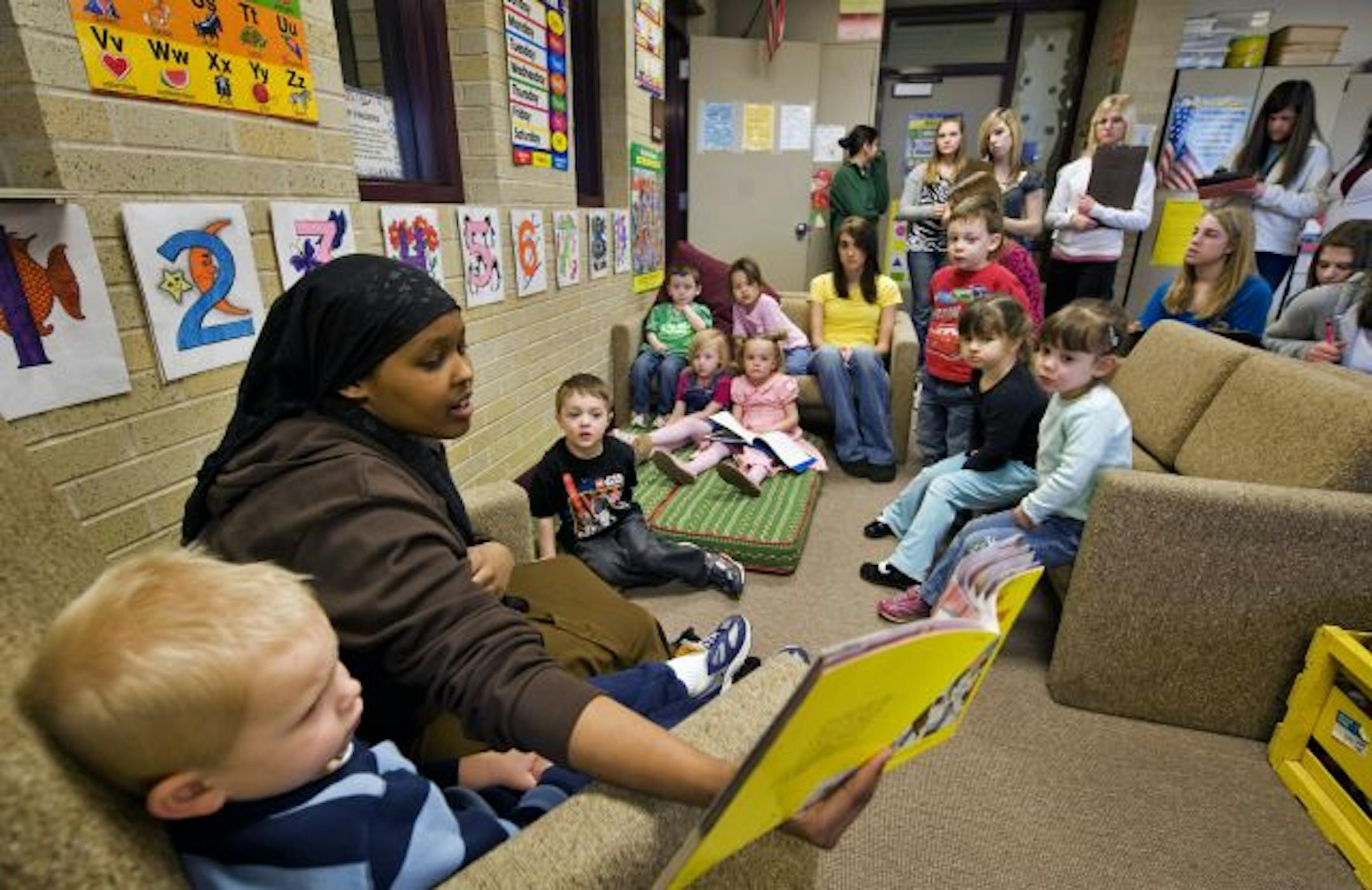 Some help from Curious George: Nanasiti Omar read a Curious George book to preschoolers during a recent reading session while other student teachers stood in back and watched. Burnsville High School runs a preschool as a way for students to gain teaching skills.
