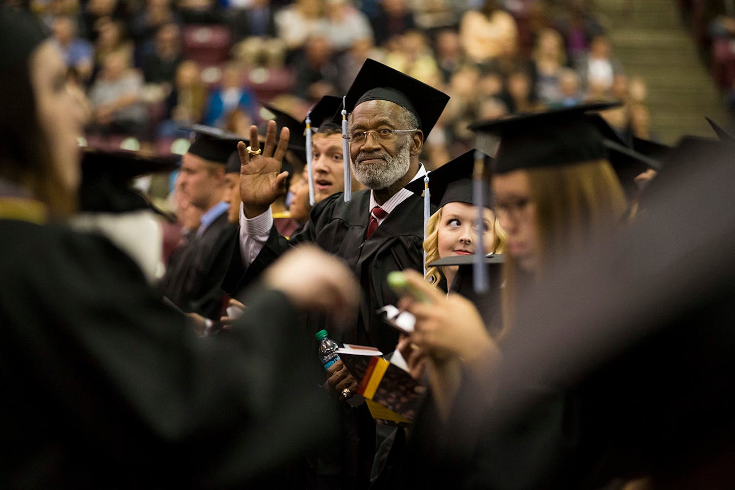 Former Gophers great and pro football Hall of Famer Bobby Bell waved to family as he waited to get his diploma as he graduated college Thursday, May 14, 2015, at Mariucci Arena.