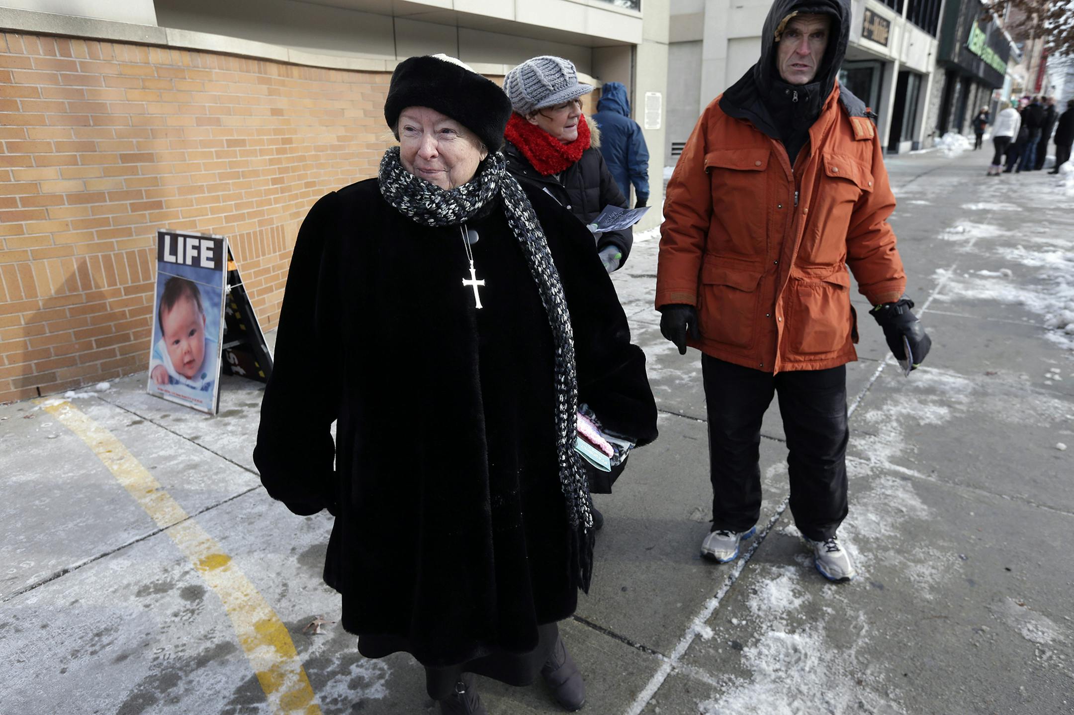 FILE - This Dec. 17, 2013 file photo shows anti-abortion protester Eleanor McCullen, of Boston, left, standing at the painted edge of a buffer zone as she protests outside a Planned Parenthood location in Boston. In a unanimous ruling Thursday, June 26, 2014, the Supreme Court struck down a 35-foot protest-free zone outside abortion clinics in Massachusetts, saying that extending a buffer zone 35 feet from clinic entrances violates the First Amendment rights of protesters. (AP Photo/Steven Senne