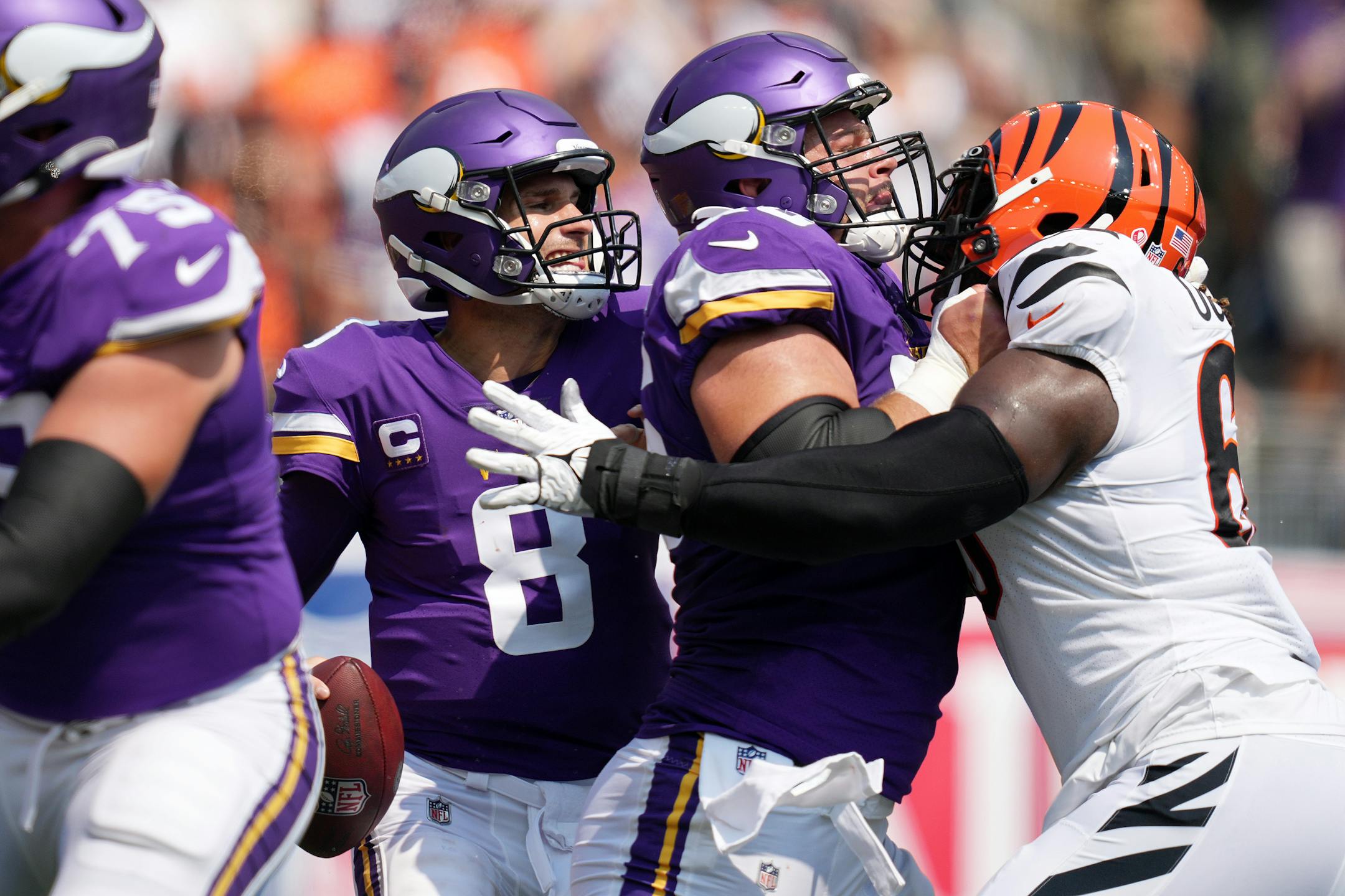Minnesota Vikings quarterback Kirk Cousins (8) searched for an open receiver as Minnesota Vikings center Garrett Bradbury (56) held back Cincinnati Bengals defensive tackle Larry Ogunjobi (65) in the first quarter.