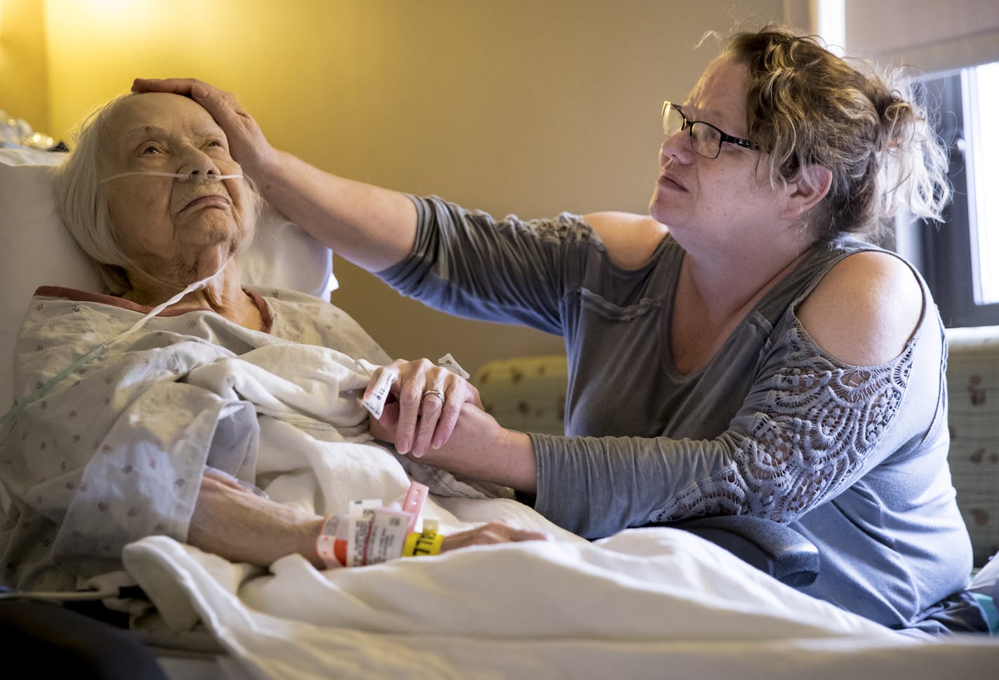 Dawn Lindberg sat with her mother, Elsa, after she was admitted to Hennepin County Medical Center. Her children have sacrificed to keep her in her home.