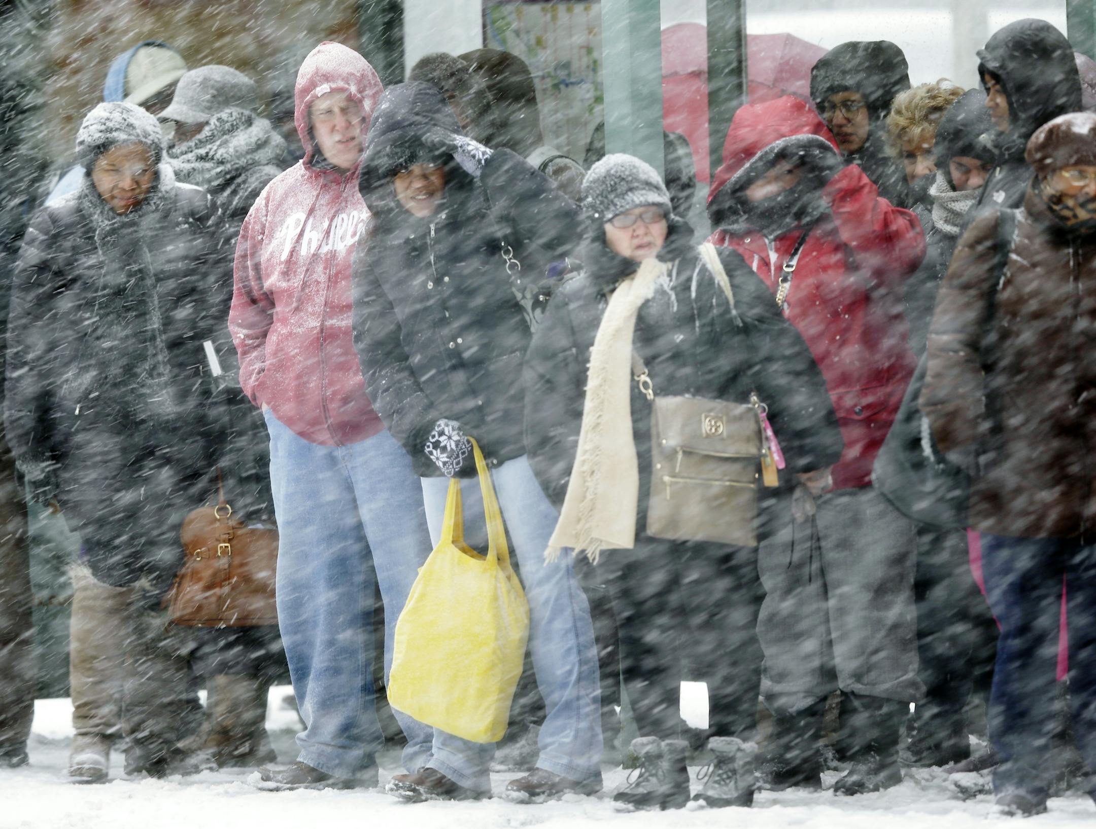 Commuters wait for a bus during a winter snowstorm Tuesday, Jan. 21, 2014, in Philadelphia as a snowstorm swept in.